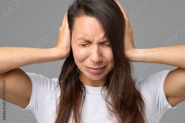Fototapeta Close-up of woman covering ears tightly with eyes closed in reaction to loud