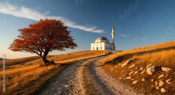 Fototapeta Picturesque view of a mosque atop a hill with a vibrant tree in the foreground