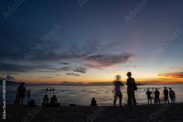 Fototapeta People watching colorful sunset on beach with calm waves and dramatic clouds over the ocean