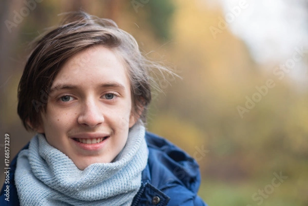 Obraz Portrait of a smiling 13-year-old teenage boy in a jacket with a scarf in an autumn park