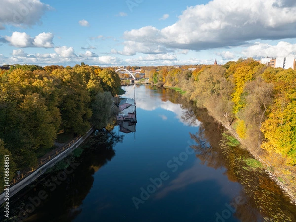 Obraz A reflective river scene with autumn trees and an arched bridge glowing in soft light.
