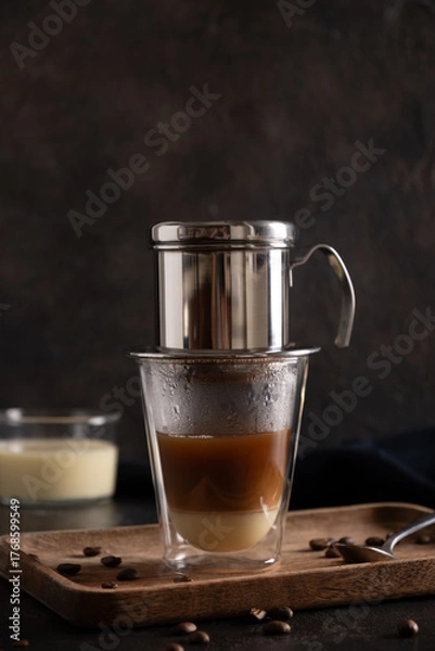 Obraz Traditional method of making Vietnamese coffee with condensed milk on black background. Close up. Vertical format.