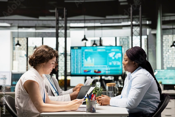 Fototapeta Diverse hiring team and black candidate discuss about qualifications for a job opening within the business organization. Evaluating CV resume information, head hunting concept. Career opportunity.