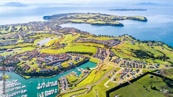 Fototapeta Aerial view on residential suburbs surrounded by sunny ocean harbour. Whangaparoa peninsula, Auckland, New Zealand