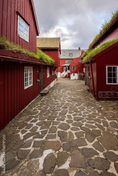 Obraz Historic cobblestone courtyard with red turf-roofed wooden houses