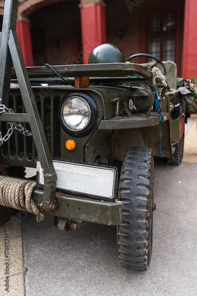 Fototapeta Classic military vehicle with chains, rope, and a helmet on display. A well-maintained vintage military vehicle.