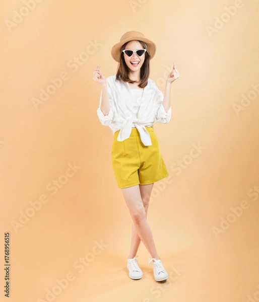 Obraz Cheerful beautiful Asian woman showing mini heart sign on beige color background, love concept.