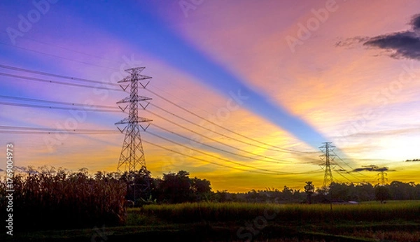 Obraz A sunset sky with bright beams of light streaking through silhouetted power poles—rural energy meets the excitement of the sky.