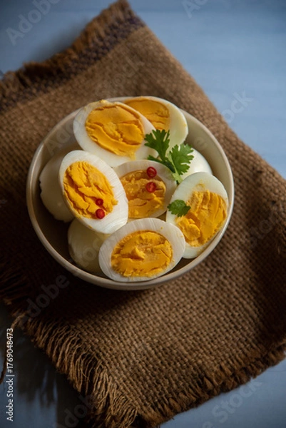 Fototapeta Sliced boiled eggs in a bowl with parsley leaves. Top view, selective focus.