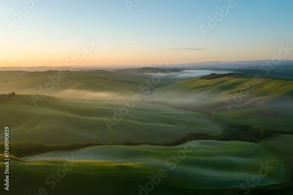 Fototapeta Serene rolling green hills bathed in the soft golden light of sunrise with ethereal mist gently rolling through the valleys creating a dreamlike atmosphere