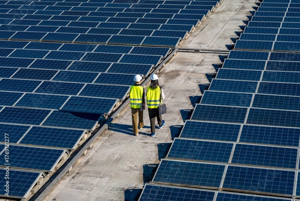 Obraz Engineers inspecting solar panels on rooftop energy farm