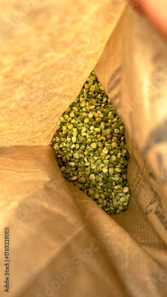 Fototapeta Split green peas inside an open paper sack