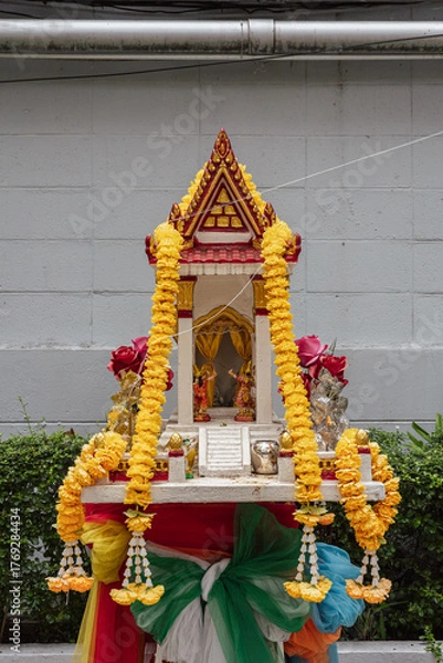 Fototapeta Traditional Thai Spirit House Decorated with Marigold Garlands in Bangkok, Thailand