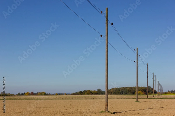 Obraz telegraph pole beside a bikeway and white tower on a plain field and wide horizon view