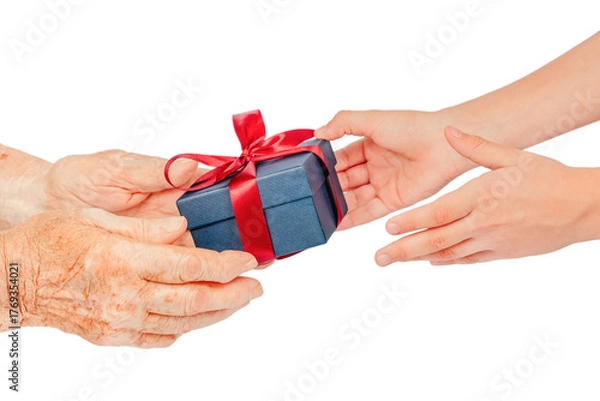 Fototapeta Close-up of elderly and young hands exchanging a blue gift box with a red ribbon, isolated on white. Symbolic concept of giving, care, gratitude, connection, family love between generations.