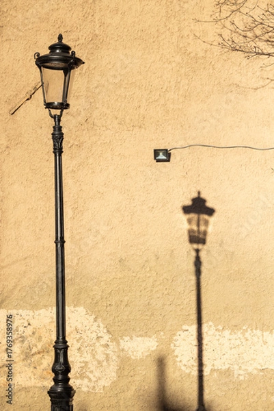 Obraz A lamppost with a shadow against a wall.