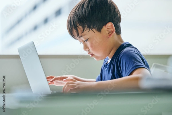Fototapeta ノートパソコンでオンライン学習をする小学生の男の子