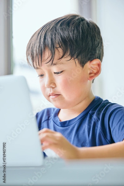 Fototapeta ノートパソコンでオンライン学習をする小学生の男の子