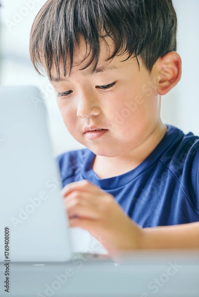 Fototapeta ノートパソコンでオンライン学習をする小学生の男の子