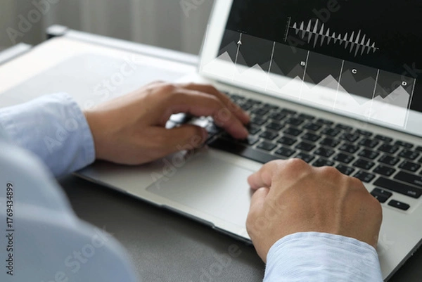 Fototapeta Businessman typing on laptop keyboard with data visualization charts overlayed, representing work, business analysis, economy, and digital productivity in modern office environment