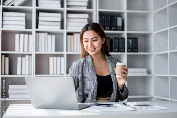 Fototapeta Accounting business concept, Accountant woman drinking coffee and typing data on laptop while working