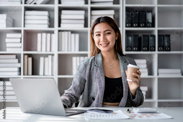 Fototapeta Accounting business concept, Accountant woman drinking coffee and typing data on laptop while working