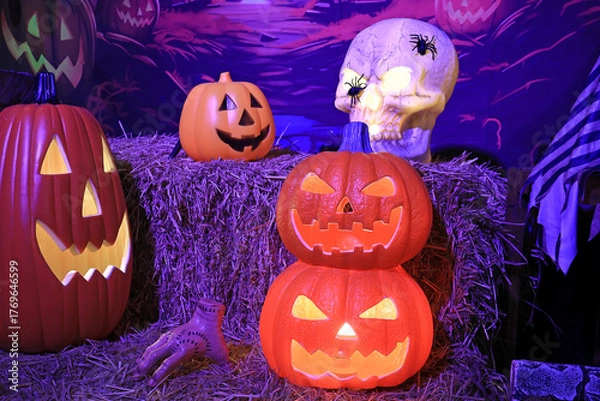 Fototapeta Closeup of Lit Halloween Jack O Lantern Pumpkins and Replica Skull in the Backyard