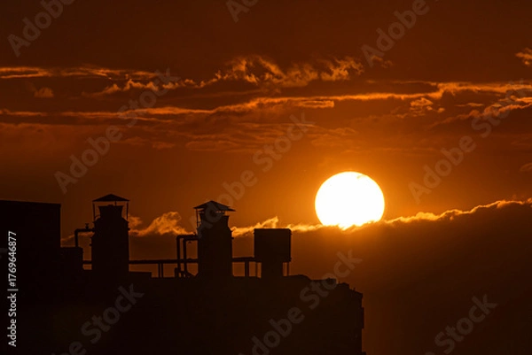 Fototapeta Sunset in the city with beautiful warm tones over the clouds