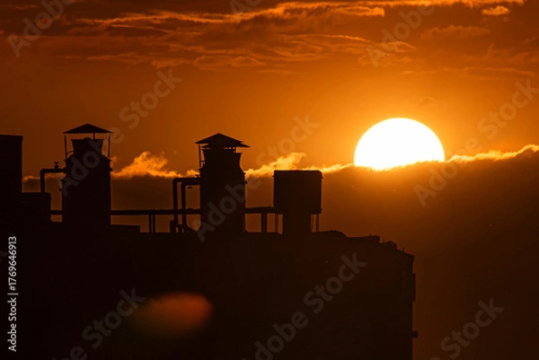 Fototapeta Sunset in the city with beautiful warm tones over the clouds