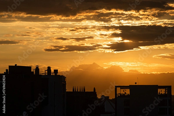 Fototapeta Sunset in the city with beautiful warm tones over the clouds