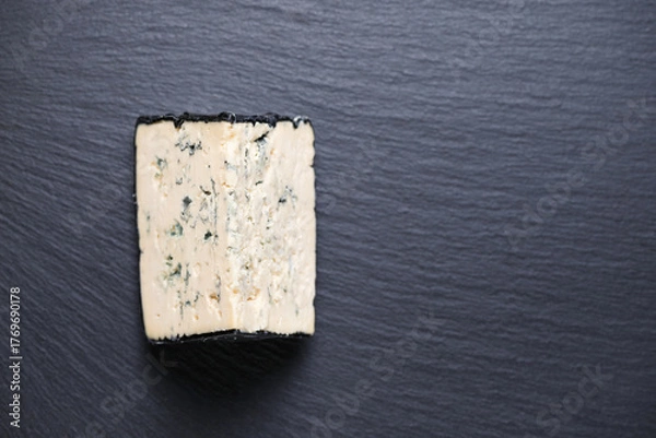 Fototapeta top view of tasty piece cheese with blue mold on black slate background, copy space