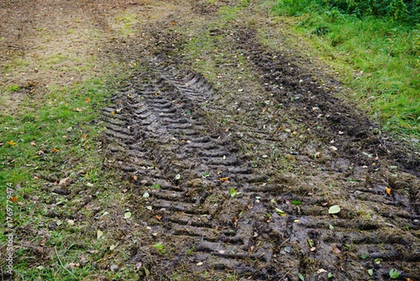 Fototapeta Traces of wheel treads on black mud, off-road, passability, tractor, field road in autumn.