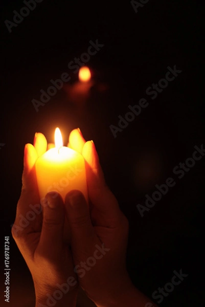 Obraz Hands holding burning candle in dark. Selective soft focus, blur smoke black, brown, yellow background.