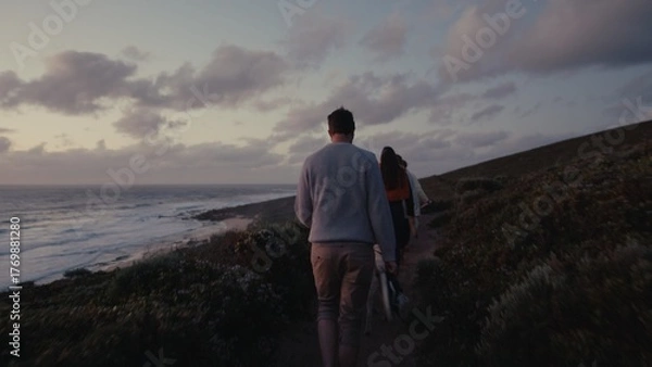 Obraz Couple walking along coastal trail at sunset near ocean waves