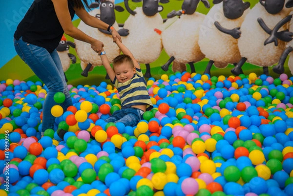 Fototapeta A boy with mother in the playing room with many little colored balls