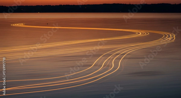 Fototapeta Long exposure light trails from boats on a calm lake at sunset.