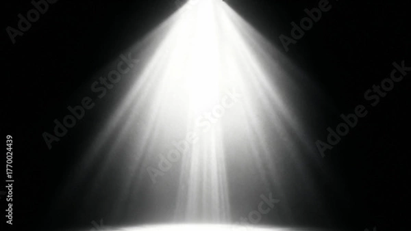 Fototapeta Bright white spotlight beam shining down from above against a dark black background creating a dramatic illuminated effect