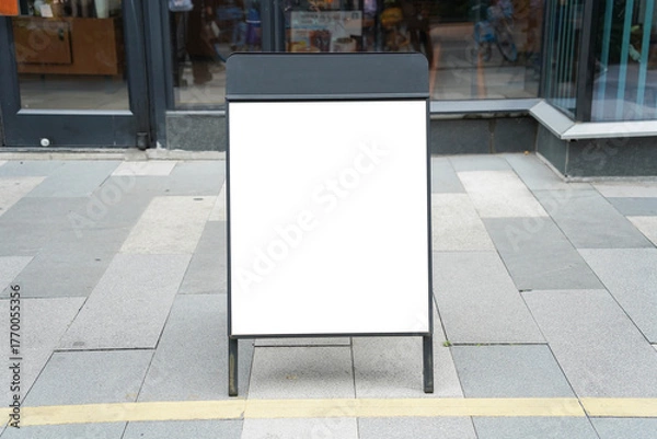 Fototapeta Blank white outdoor advertising stand or sandwich board mock up template. Clear street signage board placed by an outdoor dinning area of a restaurant. Background texture of standee on street.