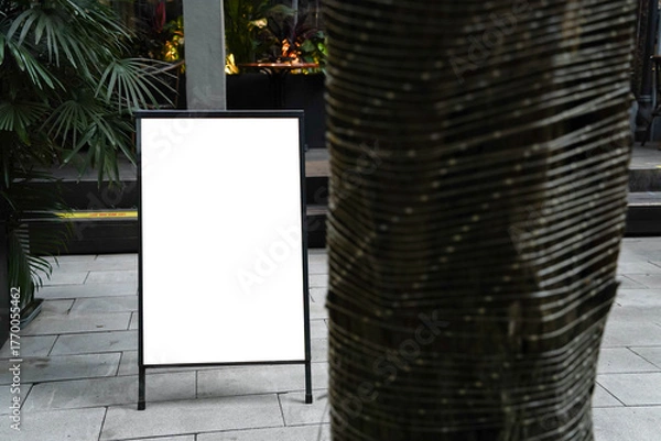 Fototapeta Blank white outdoor advertising stand or sandwich board mock up template. Clear street signage board placed by an outdoor dinning area of a restaurant. Background texture of standee on street.