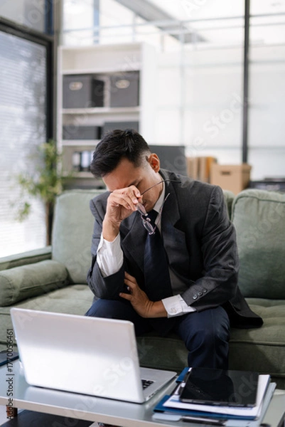 Obraz stressed Asian businessman working in the office. Businessman thinking too much work concept in the office.