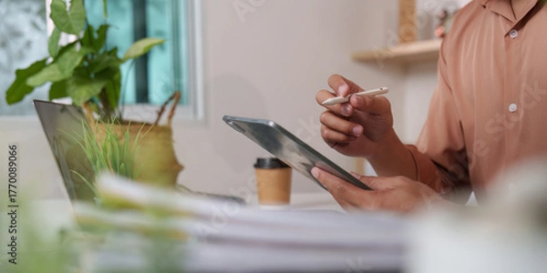 Obraz Remote Work. Professional using tablet and stylus for digital note-taking in a cozy office.