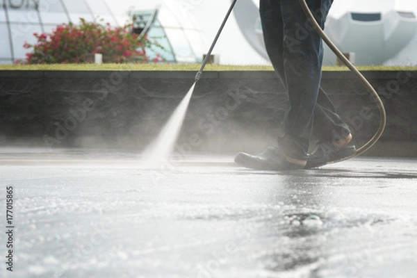 Fototapeta worker use high pressure pump to clean floor with detergent