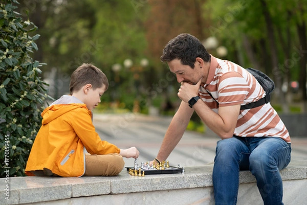 Obraz Boy with father playing chess outdoor.