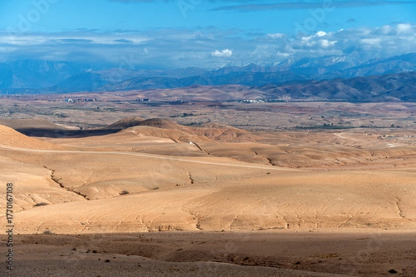 Fototapeta Vast landscape of Agafay in the Moroccan desert showing arid terrain and distant mountains