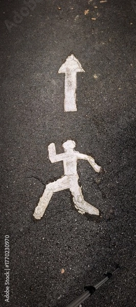 Fototapeta road marking showing a person running towards an arrow pointing up