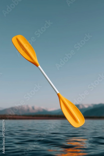 Fototapeta Bright orange kayak paddle floating in mid-air above calm lake with mountain background at sunrise
