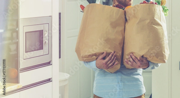 Fototapeta man holds paper bags with food in hands