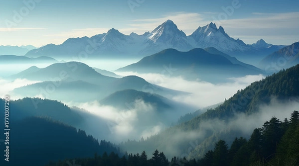 Fototapeta Majestic snow-capped mountain peaks emerge from ethereal morning mist blanketing lush green valleys below