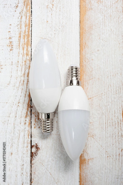 Fototapeta Two LED lamps with E14 sockets lying on a wooden surface.