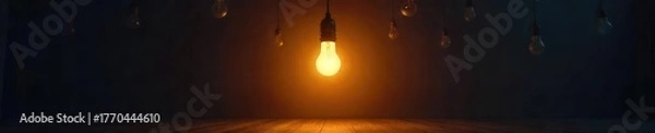 Obraz A single lightbulb illuminates a dark room, casting a dramatic spotlight effect Several other unlit bulbs hang overhead, suggesting potential and untapped ideas , breakthrough, discovery